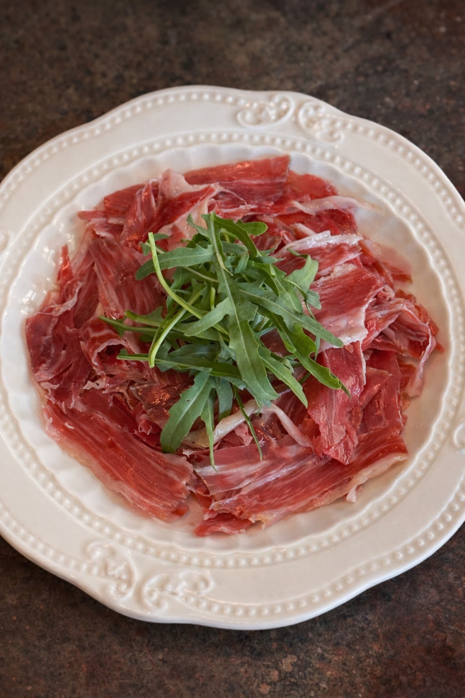 Thinly sliced cured meat plated at Somaha