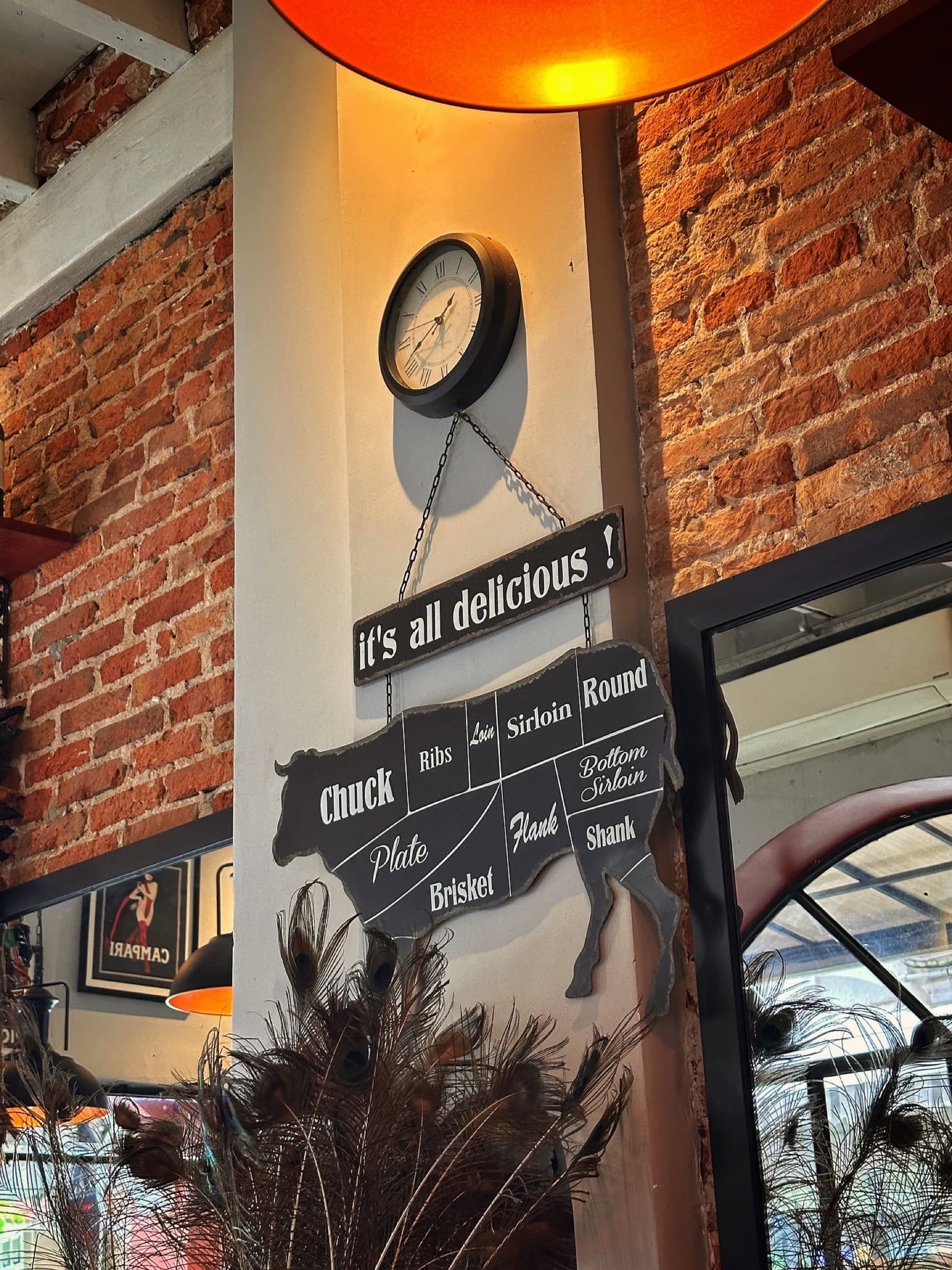 A butcher's cut chart and an 'it's all delicious!' sign hanging on Somaha's exposed brick wall